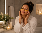 Woman applying eye masks in a bathroom with candles and flowers.